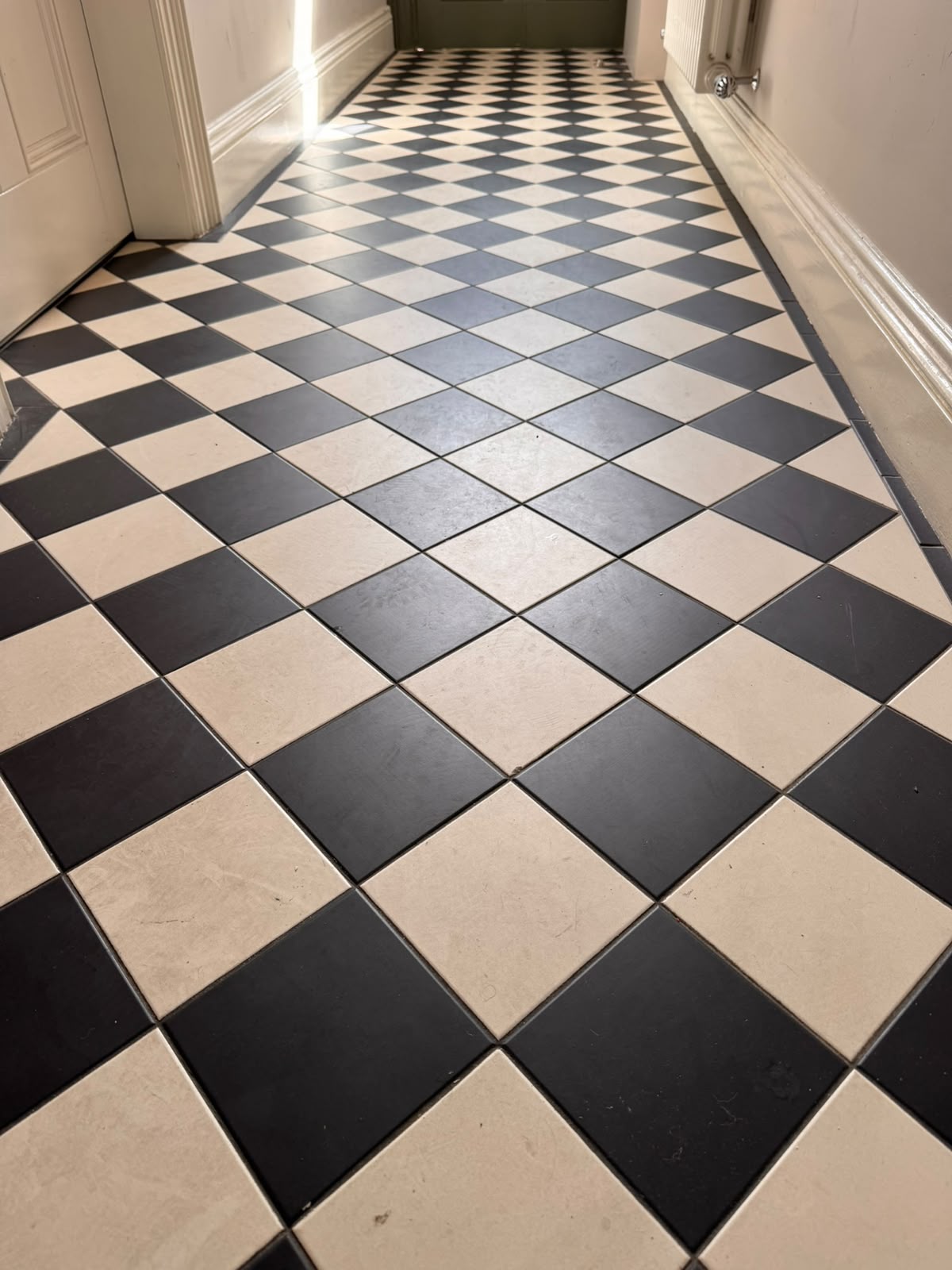 Black and cream chequerboard hallway tiles before cleaning — dull, grey and marked