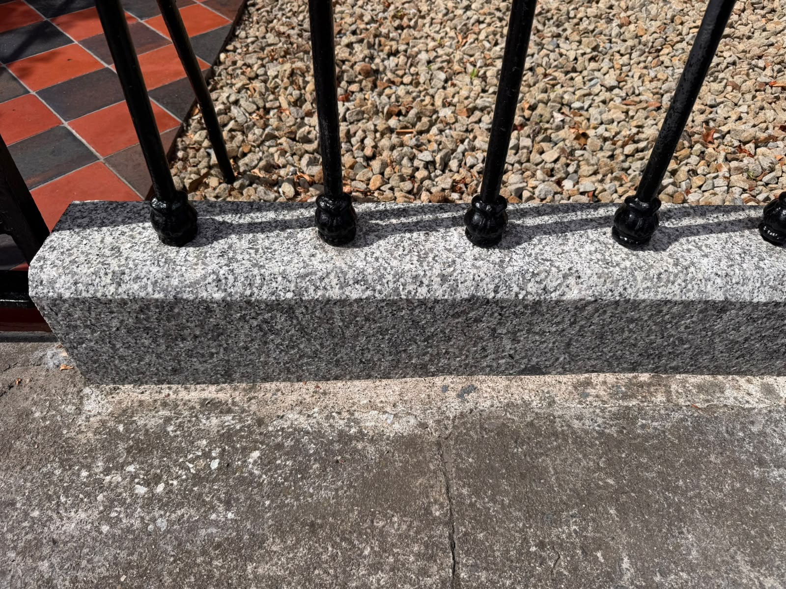 The same granite plinth after cleaning — rust and algae removed, natural grey granite restored