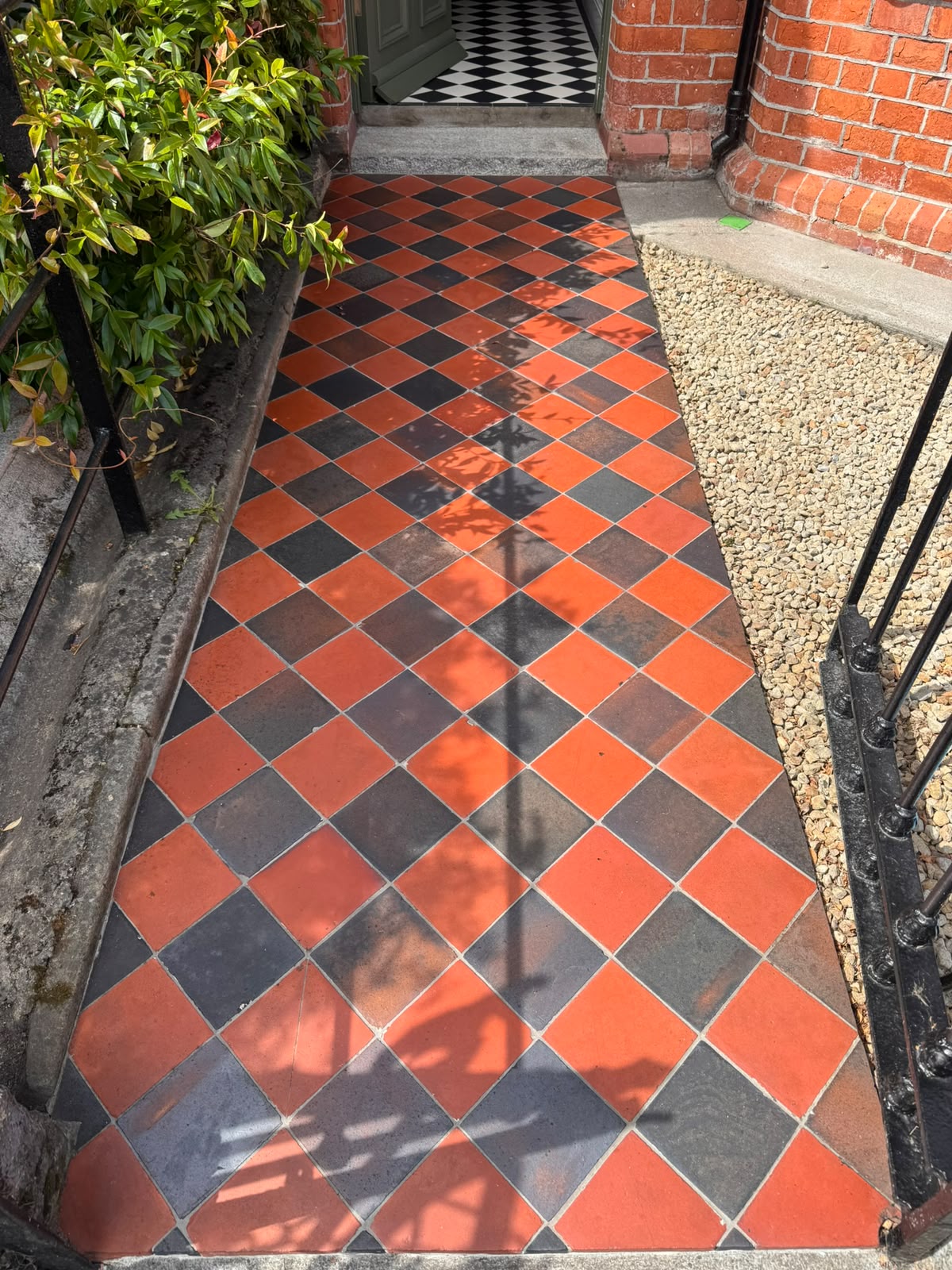 The same Victorian quarry tile path after restoration — deep red and charcoal tiles cleaned and colour restored