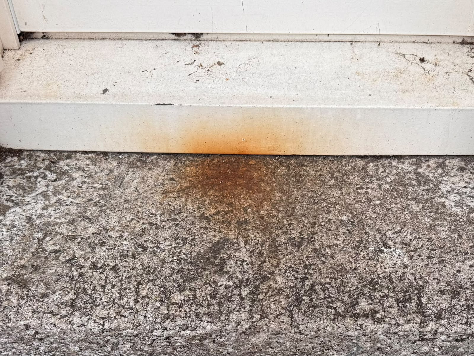 Granite window plinth before treatment — deep orange rust staining across the stone